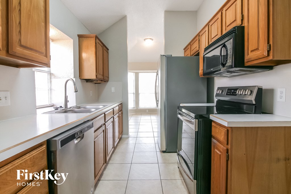 a kitchen with wood cabinets and black appliances and white counter tops