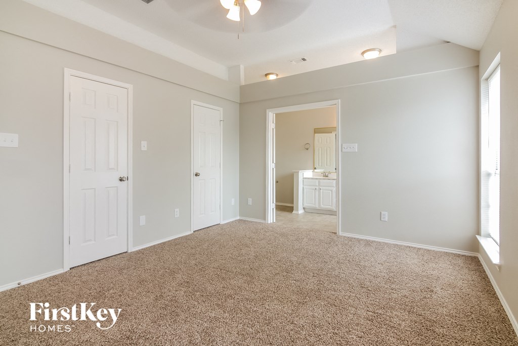 a master bedroom with a carpeted floor and a door to a bathroom