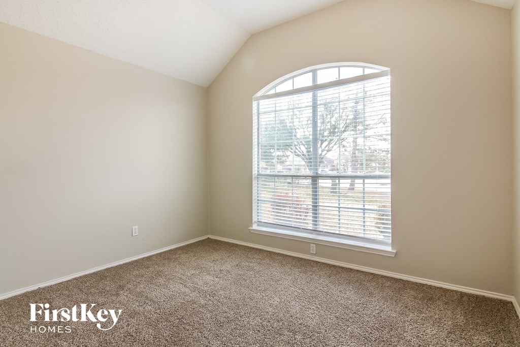 a bedroom with a large window and carpeting