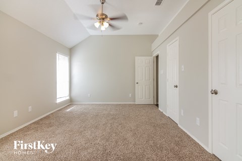 a spacious living room with carpet and a ceiling fan