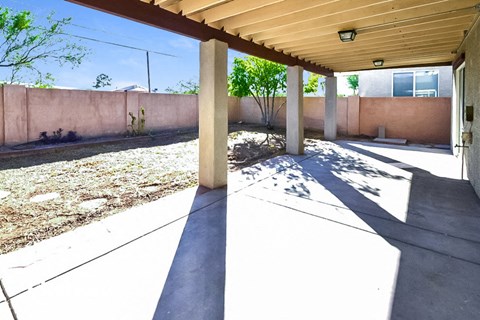 a patio with a wall and trees in the background