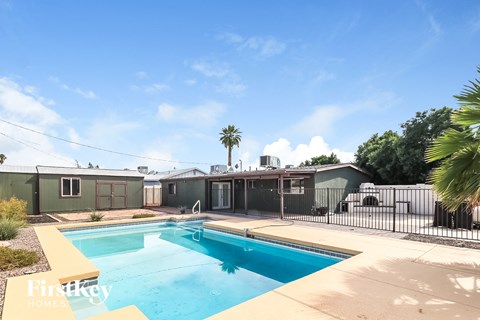 a swimming pool in front of a house with a fence