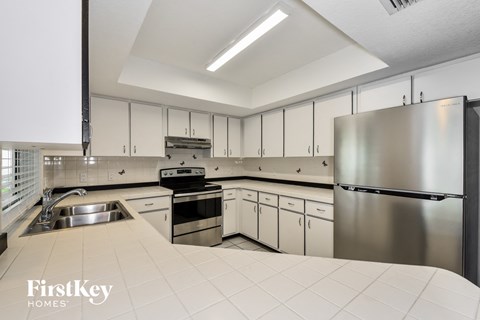 a white kitchen with stainless steel appliances and white counter tops