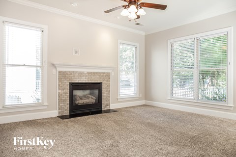 A living room with a fireplace and a ceiling fan.