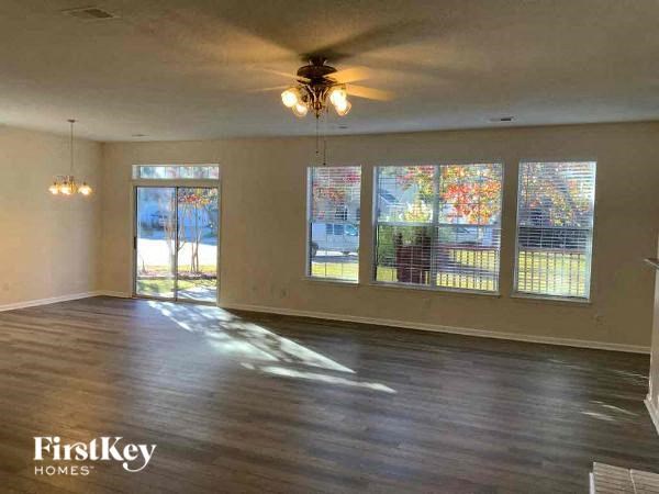an empty living room with wood floors and a ceiling fan