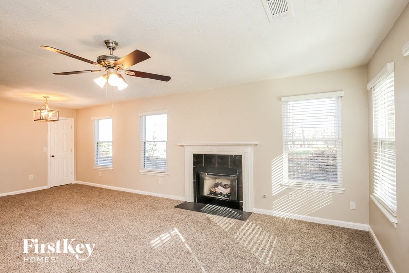 A living room with a fireplace and a ceiling fan.