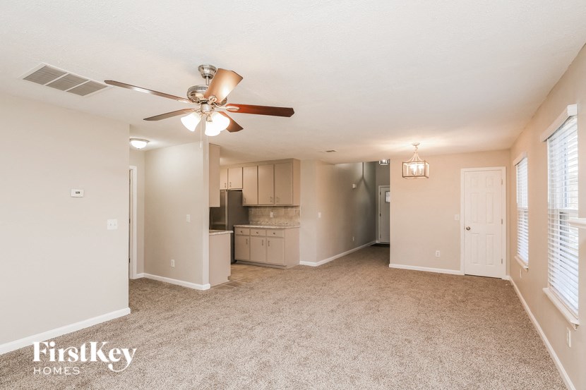 A spacious room with a ceiling fan and carpeted floor.