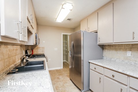 A kitchen with a stainless steel refrigerator and a granite countertop.