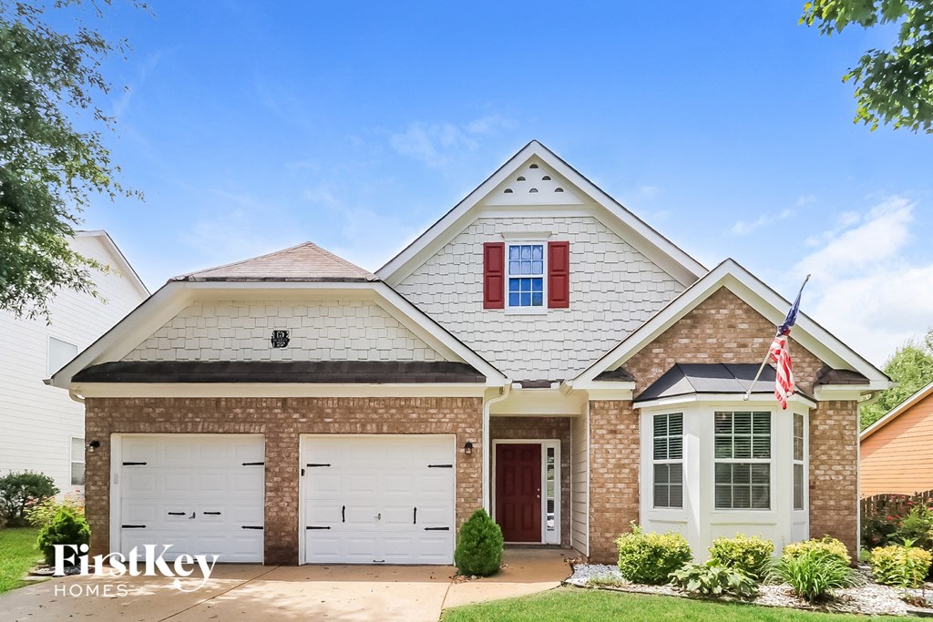 a brick house with white garage doors and a flag on the side
