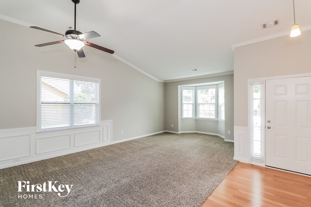 an empty living room with a ceiling fan and a window