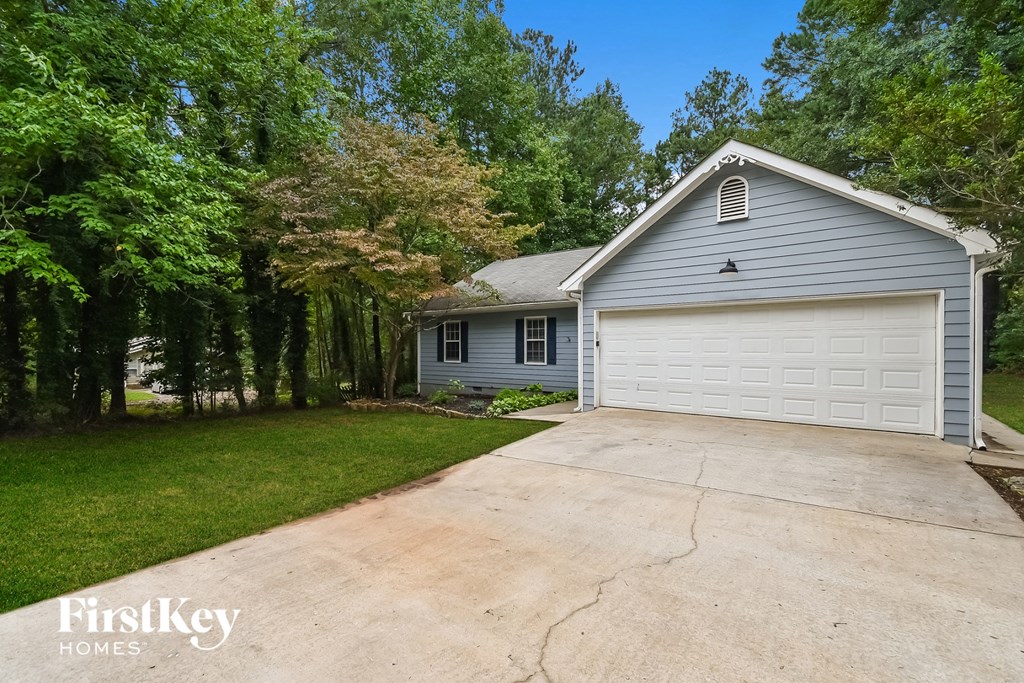 A house with a garage is surrounded by trees.