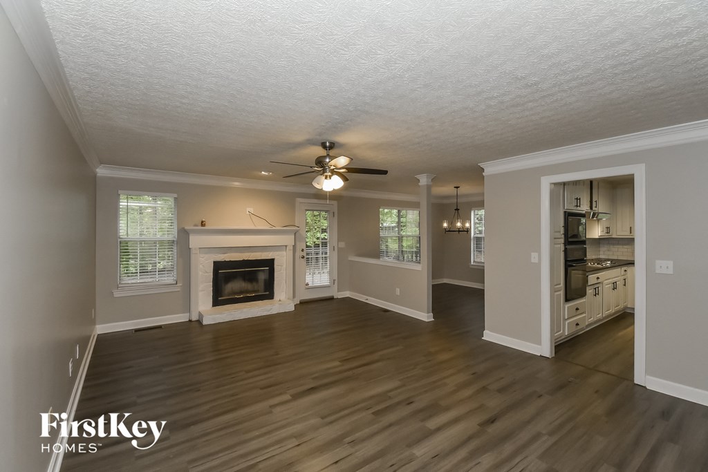 A spacious living room with a fireplace and a kitchen area in the background.