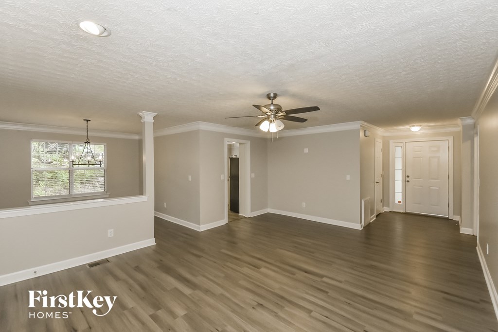 A spacious room with a ceiling fan and wooden flooring.