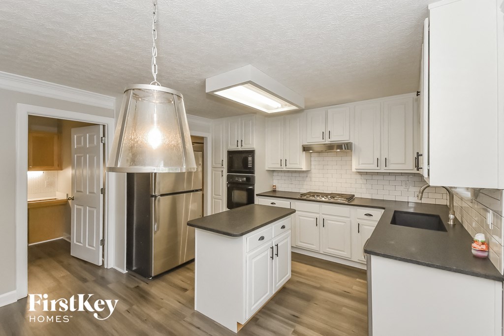 A kitchen with white cabinets and a stainless steel refrigerator.