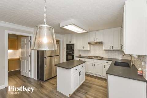 A kitchen with white cabinets and a stainless steel refrigerator.