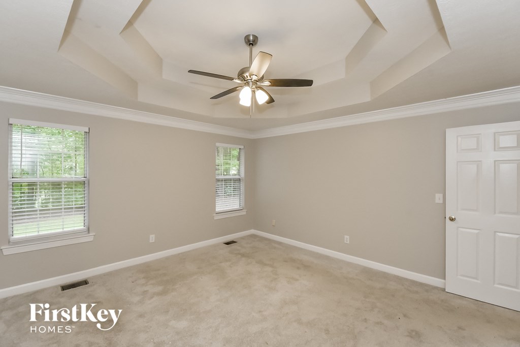 A spacious room with a ceiling fan and a door on the right side.