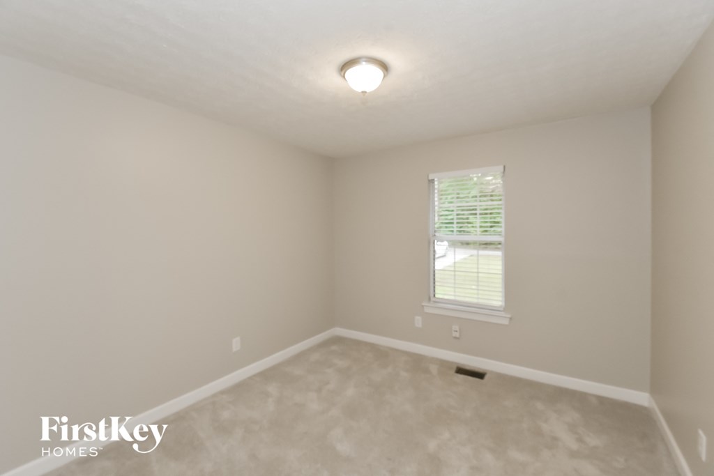 A room with a window and a carpeted floor.