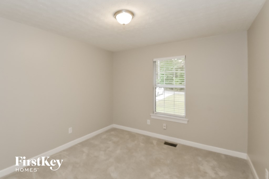 A room with a window and a carpeted floor.