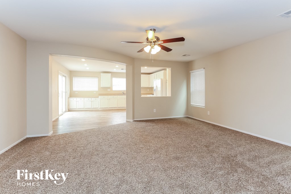 A spacious room with a carpeted floor and a ceiling fan.