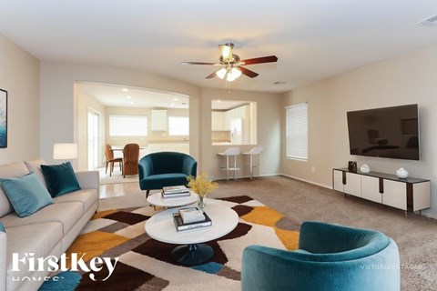 A living room with a white couch, blue armchair, and a coffee table with a vase of flowers on it.