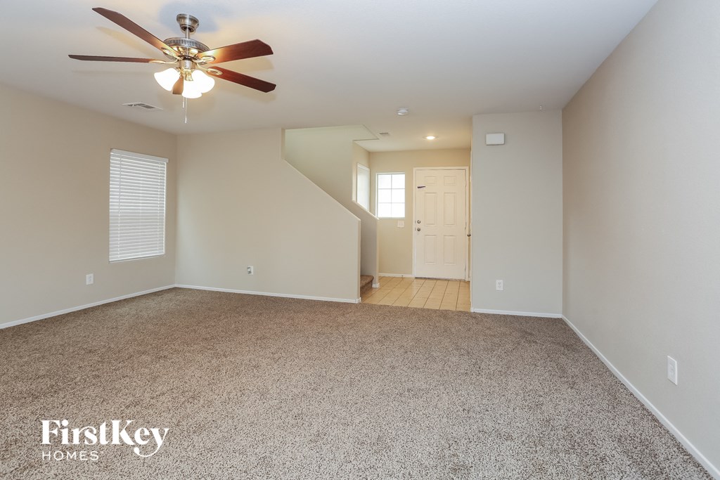 A spacious room with a ceiling fan and carpeted floor.