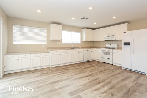 A kitchen with white cabinets and a wooden floor.