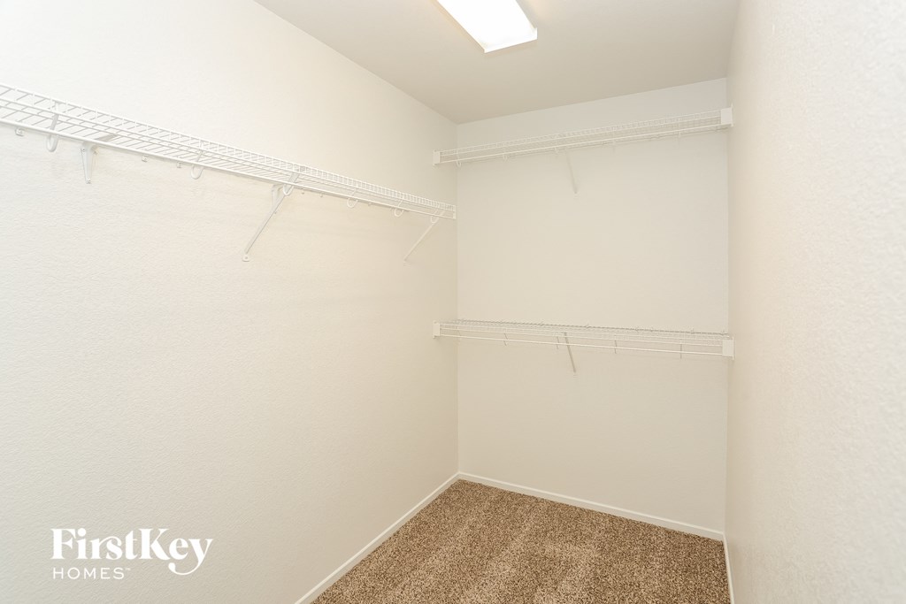 A white bedroom with a carpeted floor and a white wall.