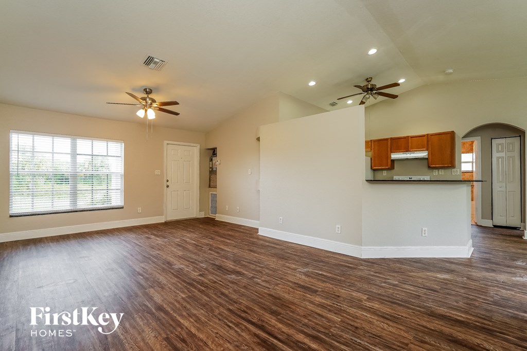 A spacious room with wooden floors and a ceiling fan.