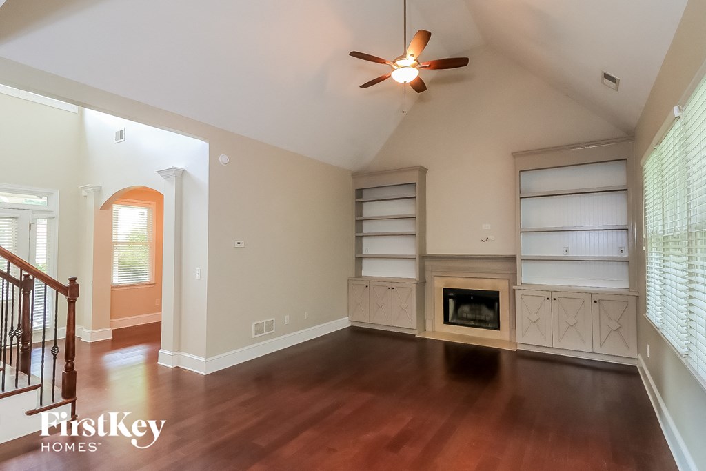 an empty living room with a fireplace and a ceiling fan