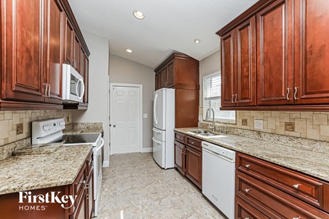 a kitchen with wood cabinets and white appliances and granite counter tops