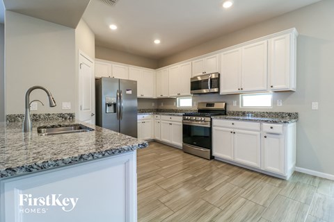 a kitchen with white cabinets and granite counter tops and stainless steel appliances