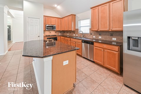 A kitchen with brown cabinets and a black countertop.