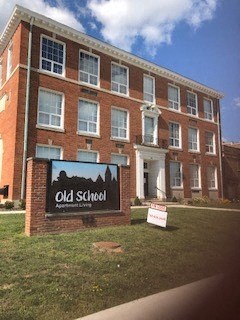 an old school sign in front of a brick building