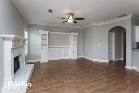 a living room with a fireplace and a ceiling fan