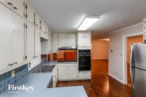 a kitchen with white cabinets and a black stove and a refrigerator