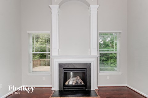 a fireplace in a living room with white pillars and windows