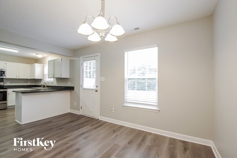 a living room with a kitchen and a chandelier