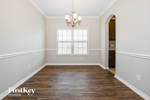 A room with wooden floors and a chandelier hanging from the ceiling.