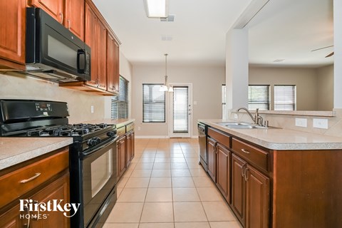 A kitchen with wooden cabinets and a black microwave.