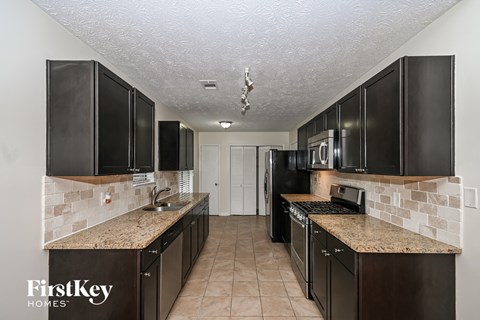 A kitchen with black cabinets and a granite countertop.
