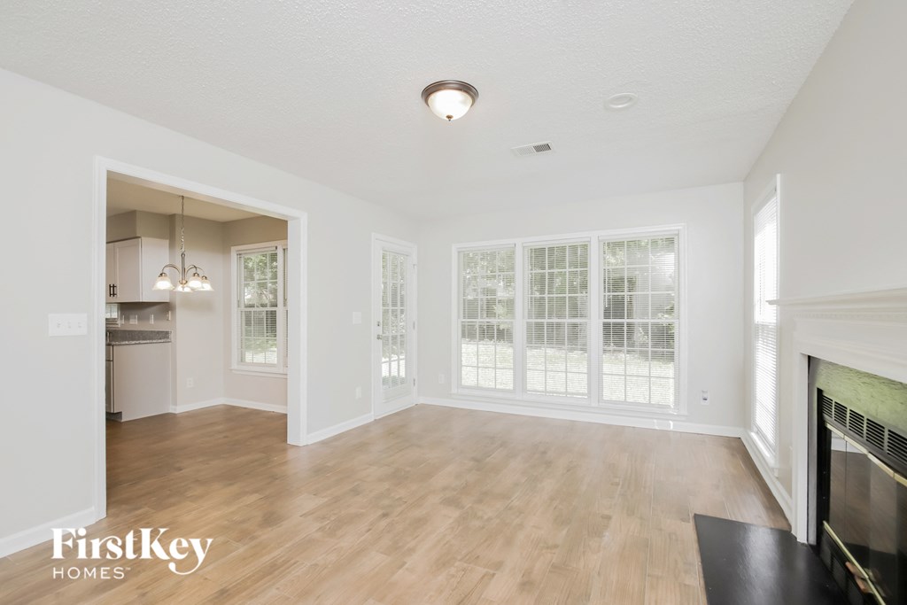 an empty living room with a fireplace and wood flooring