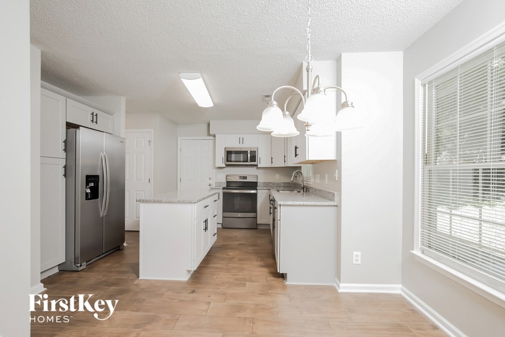a renovated kitchen with white cabinets and stainless steel appliances