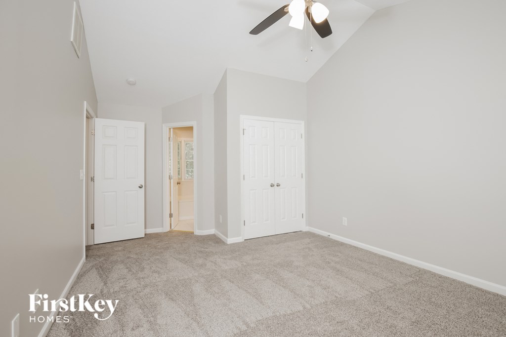 a living room with carpet and white doors and a ceiling fan