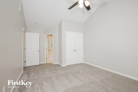 a living room with carpet and white doors and a ceiling fan
