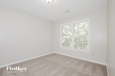 a bedroom with white walls and carpet and a window