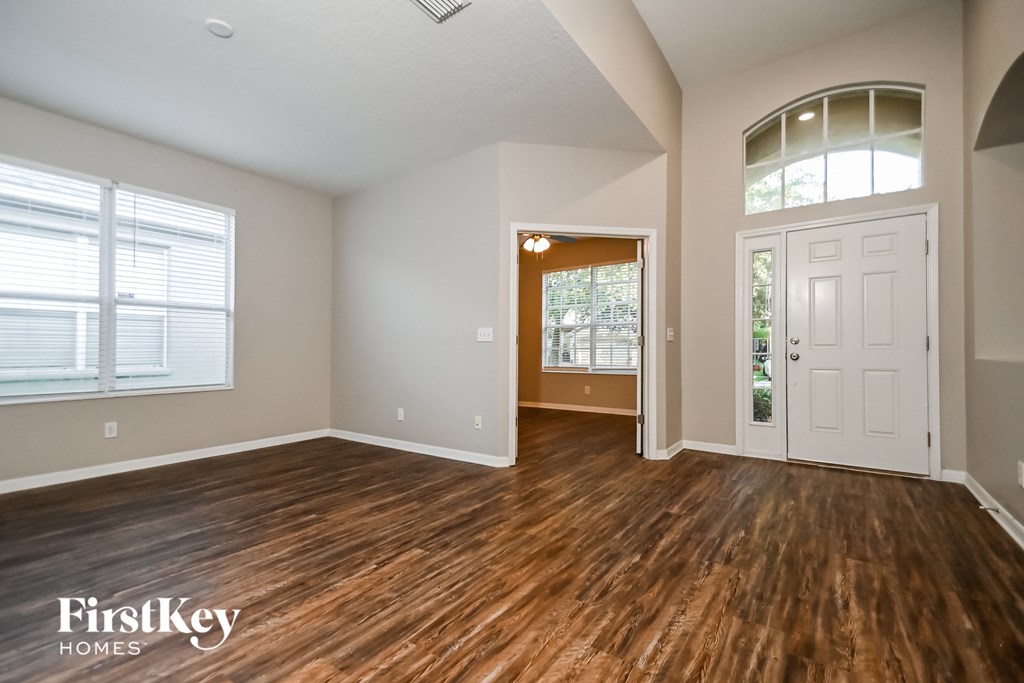 the living room of an empty house with wooden floors and a white door