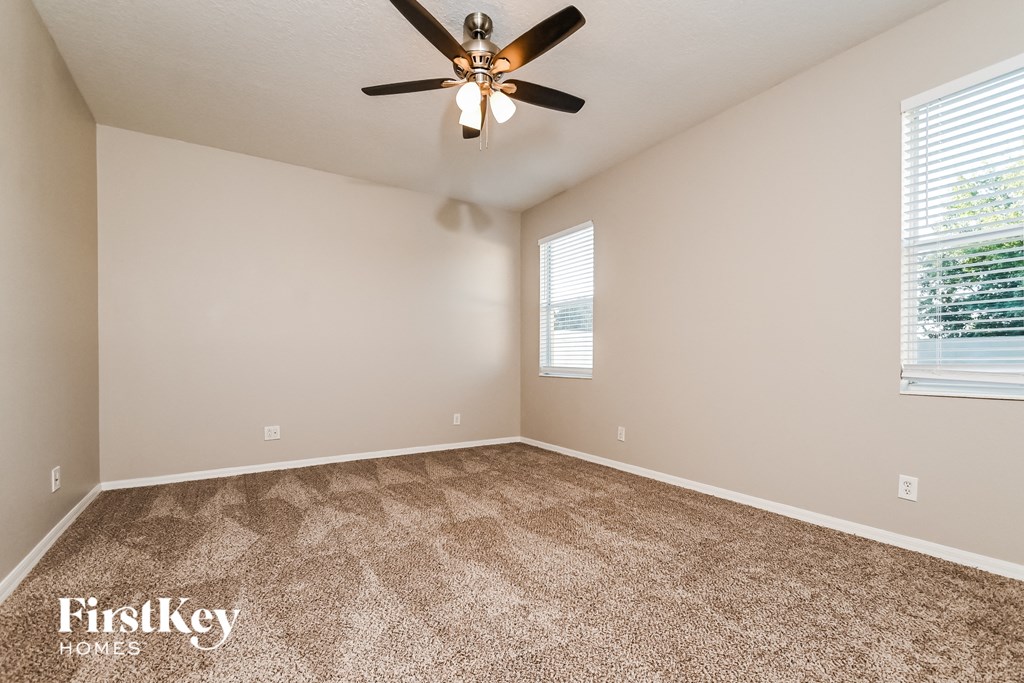 the spacious living room with carpeting and a ceiling fan
