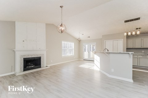 a living room with a fireplace and a kitchen with white cabinets
