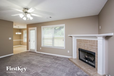 A spacious living room with a fireplace and a ceiling fan.