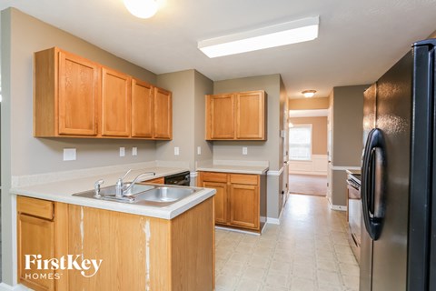 A kitchen with wooden cabinets and a black refrigerator.